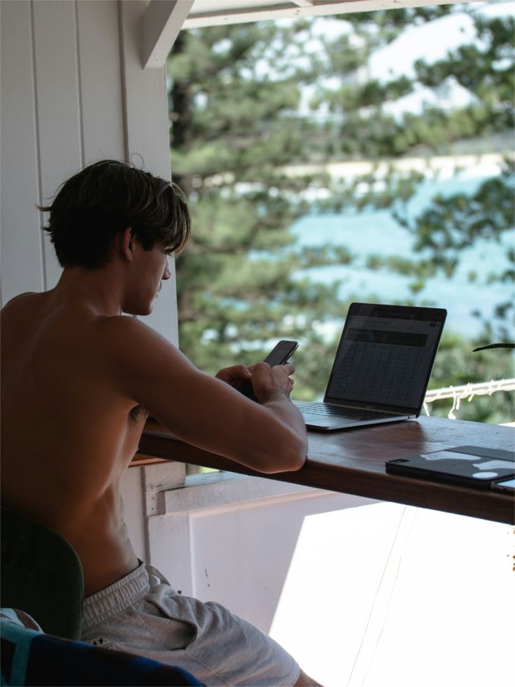 Benjamin working on his laptop from a balcony overlooking the ocean in Bali